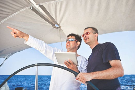 Skipper using digital tablet on sailboat